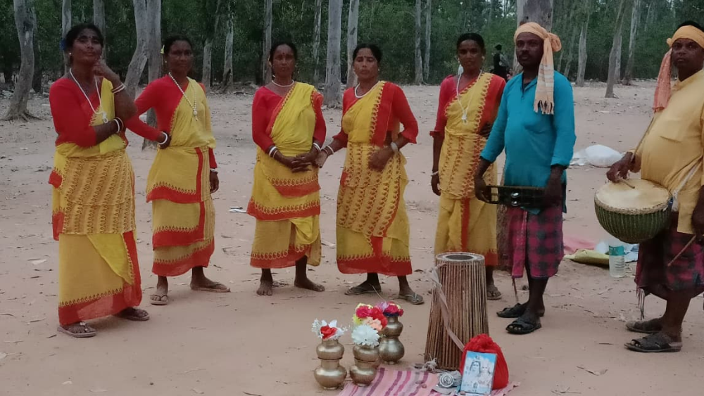 A group of Baul singers and folk dancers in traditional yellow and red sarees performing in the forests of Santiniketan, Birbhum.